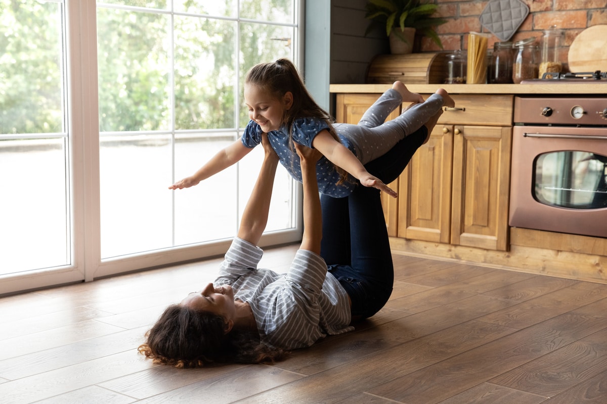 young mom lifting little daughter up doing exercise together