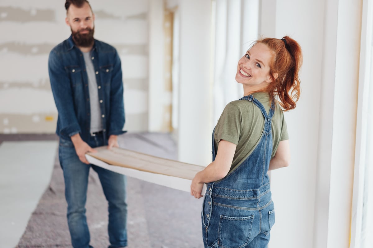 smiling woman assisting her husband doing diy